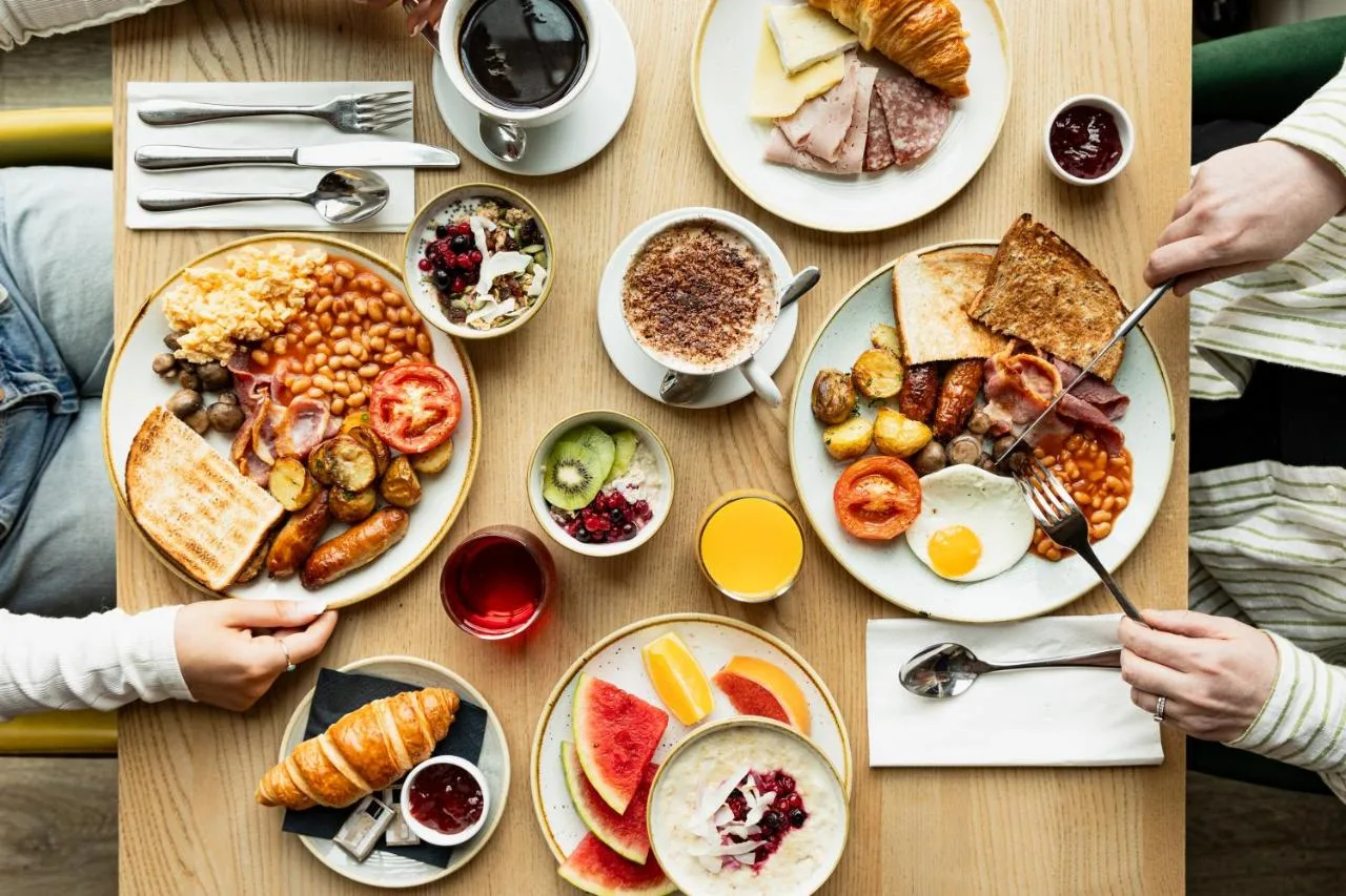 a table with plates of breakfast food on it at Leonardo Hotel Bristol City in Bristol
