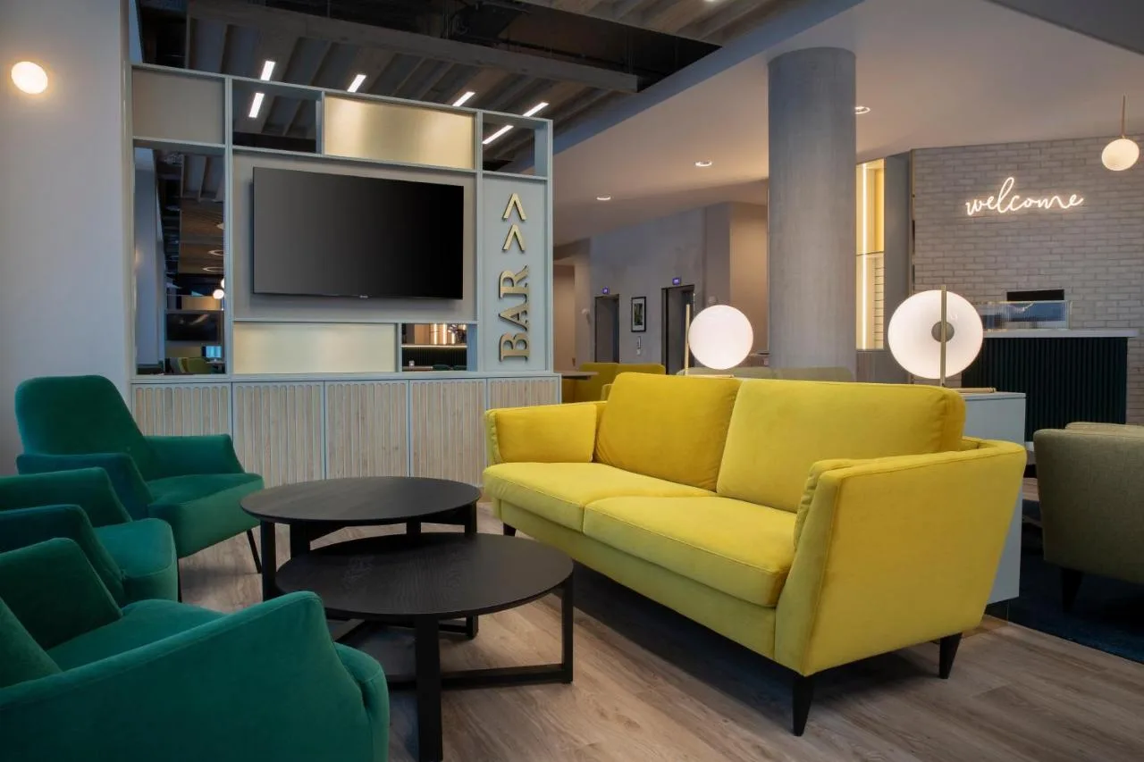 a living room with a yellow couch and chairs at Leonardo Hotel Bristol City in Bristol