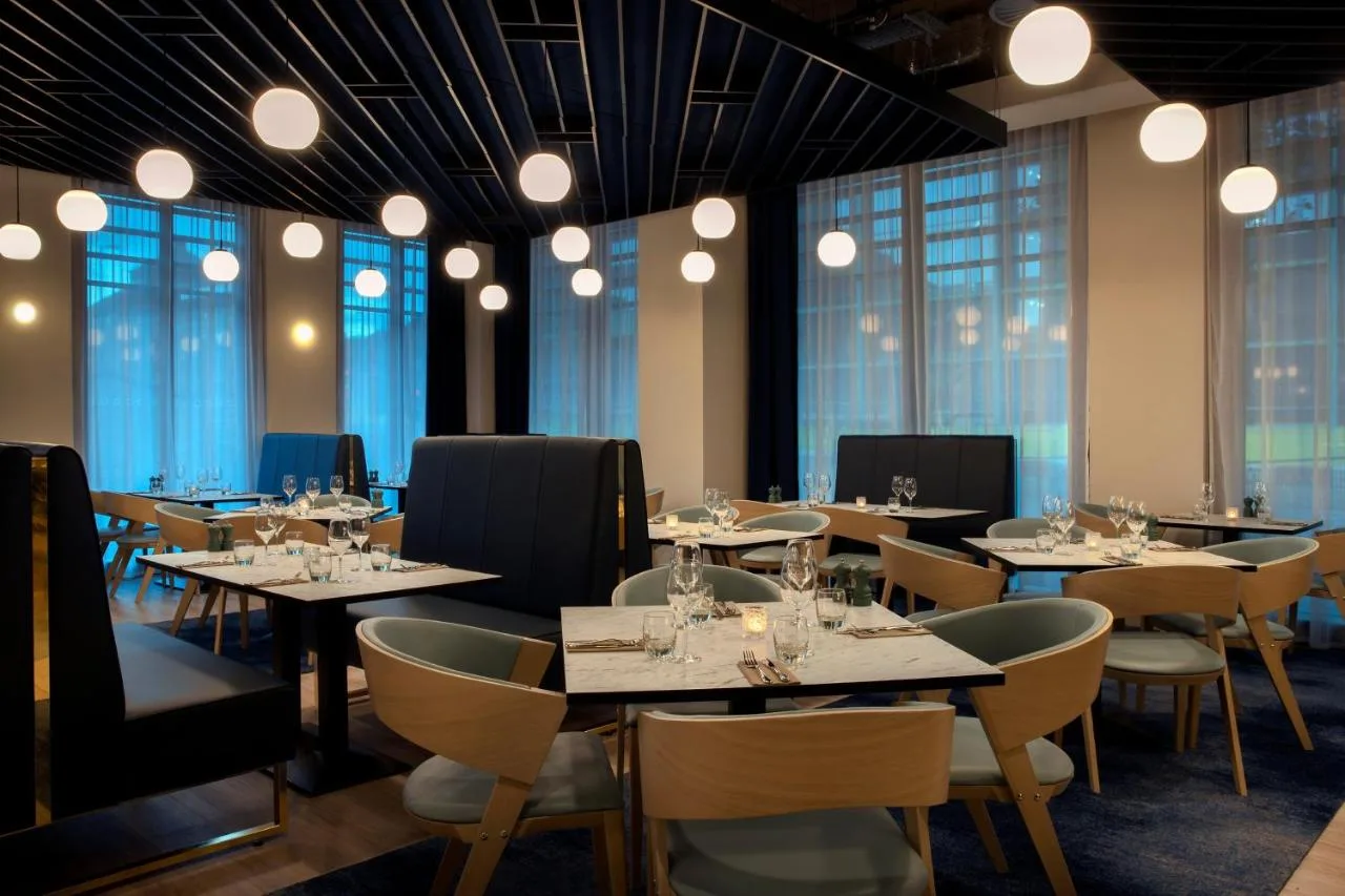 a dining room with tables and chairs and windows at Leonardo Hotel Bristol City in Bristol