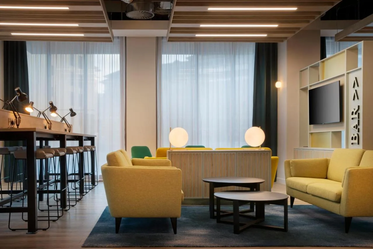 a waiting room with yellow chairs and a bar at Leonardo Hotel Bristol City in Bristol